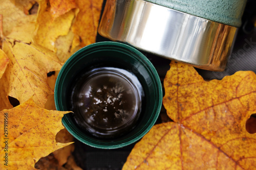 Green thermos stailess steel cup in autumn leaves photo