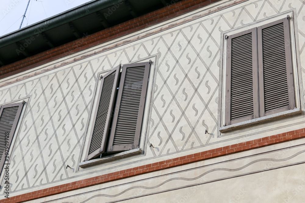 Italian  façade: finely decorated walls and window with blinders in an old, heritage building in a court in Milan.