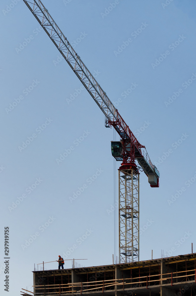 Landscape construction of a large building. There is a tall construction crane and building frame. A small human figure does the work in the lower left corner of the frame. Background. Decoration. Landscape construction of a large building. There is a tall construction crane and building frame. A small human figure does the work in the lower left corner of the frame. Background. Decoration.