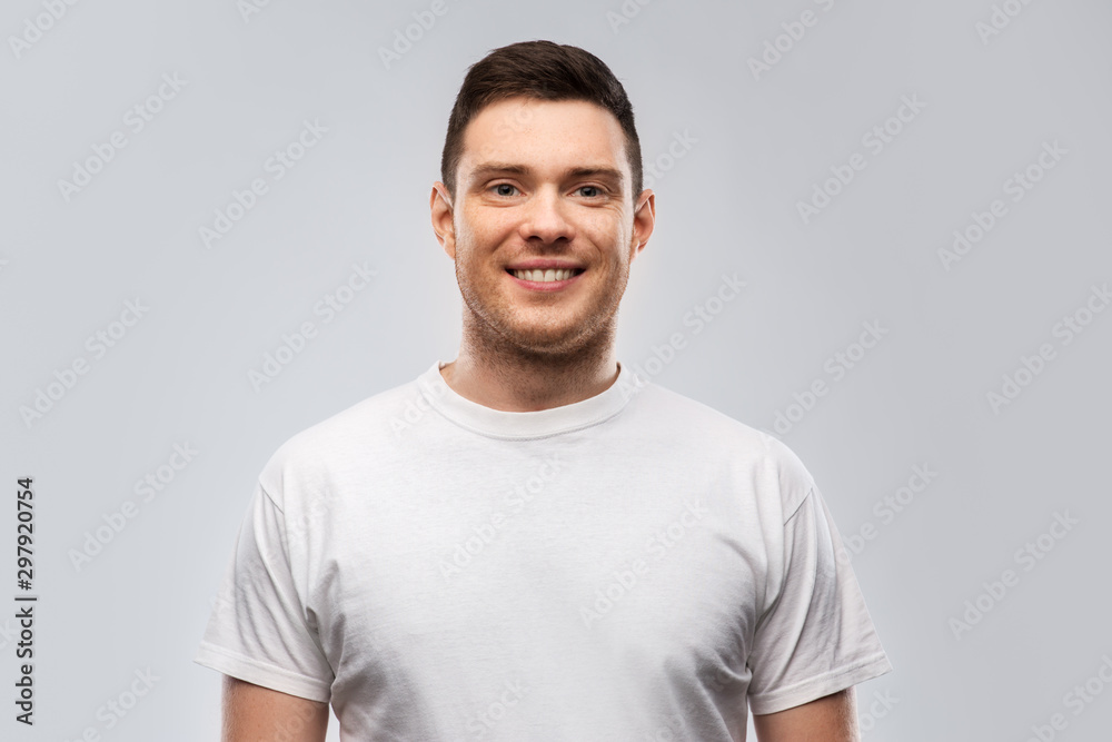 people concept - portrait of smiling young man in white t-shirt over grey background people concept - portrait of smiling young man in white t-shirt over grey background