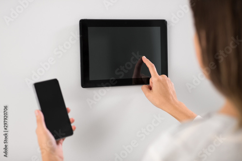 automation, internet of things and technology concept - woman using tablet pc computer and smartphone at smart home