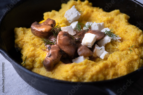 Traditional Eastern European corn mush (mamaliga, polenta, banosh, balmes) topped with sheep cheese, mushroom gravy, fried meat pieces