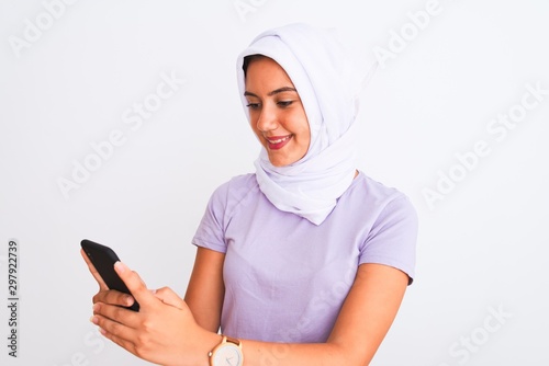 Young beautiful arabian girl wearing hijab using smartphone over isolated white background with a happy face standing and smiling with a confident smile showing teeth