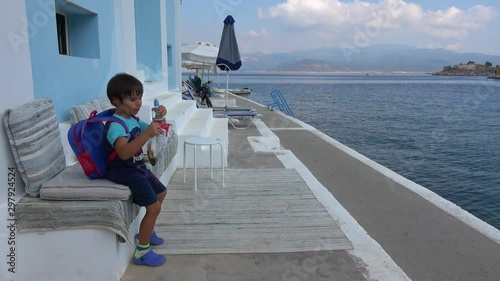 Castellorizo island, Greece - 1st of October 2019: 4K Kid with snack and water rested at the waterfront photo