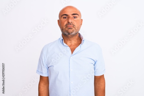 Middle age handsome man wearing casual shirt standing over isolated white background with serious expression on face. Simple and natural looking at the camera.