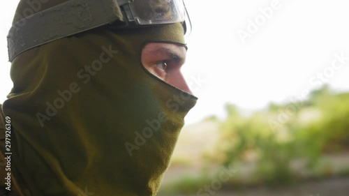 Young soldier in military uniform remove cloth mask on his face. Airsoft game. Close up shot.