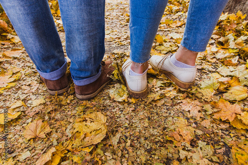 Womans and mans boots on dry fall leaves in the nature park outdoor and autumn season
