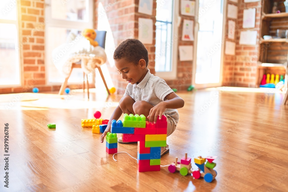 Beautiful african american toddler playing with building blocks smiling at kindergarten - obrazy, fototapety, plakaty 