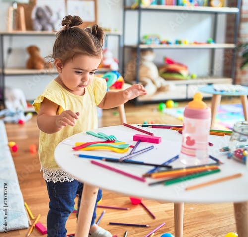 Beautiful toddler standing playing with toys on the table at kindergarten