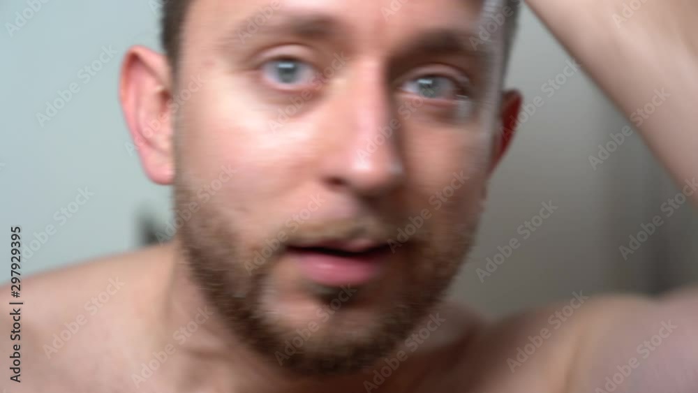 Blue eyes man brushing his stylish beard in front of a mirror. Handsome boy doing routine morning procedures in the bathroom, facial hair treatment with exclusive products from barber shop. Shaving Blue eyes man brushing his stylish beard in front of a mirror. Handsome boy doing routine morning procedures in the bathroom, facial hair treatment with exclusive products from barber shop. Shaving