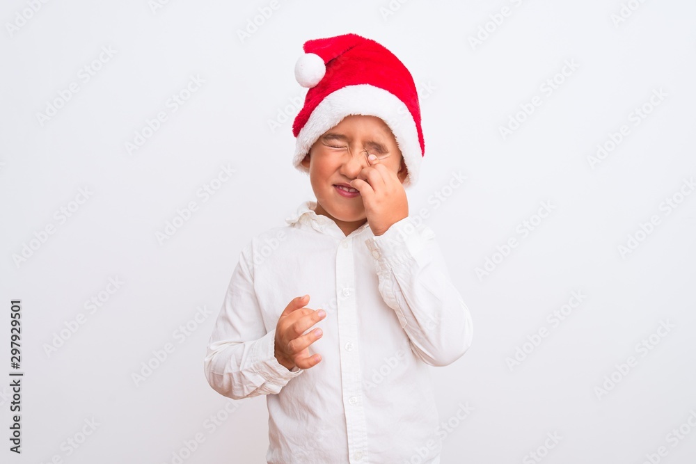 Beautiful kid boy wearing Christmas Santa hat standing over isolated white background winking looking at the camera with sexy expression, cheerful and happy face. Beautiful kid boy wearing Christmas Santa hat standing over isolated white background winking looking at the camera with sexy expression, cheerful and happy face.
