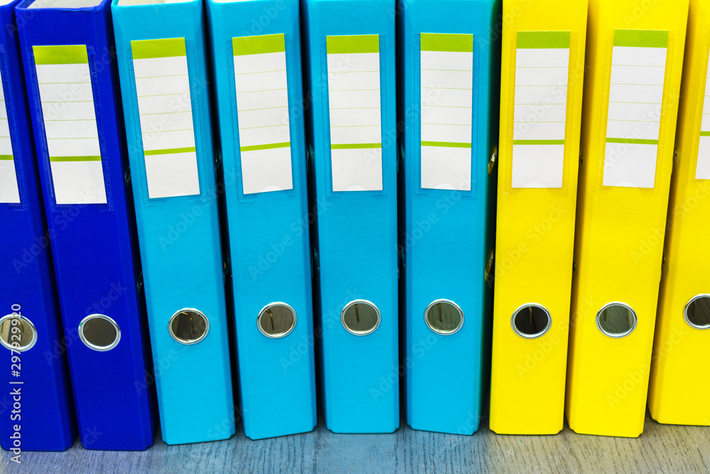Row from the blue yellow file folders with clean blank for your text. Large stationery folders, paperwork abstract background Row from the blue yellow file folders with clean blank for your text. Large stationery folders, paperwork abstract background