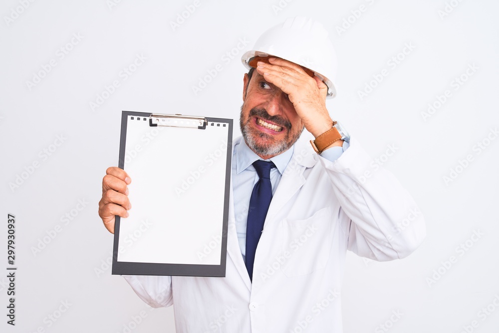 Senior engineer man wearing security helmet holding clipboard over isolated white background stressed with hand on head, shocked with shame and surprise face, angry and frustrated. Fear and upset Senior engineer man wearing security helmet holding clipboard over isolated white background stressed with hand on head, shocked with shame and surprise face, angry and frustrated. Fear and upset