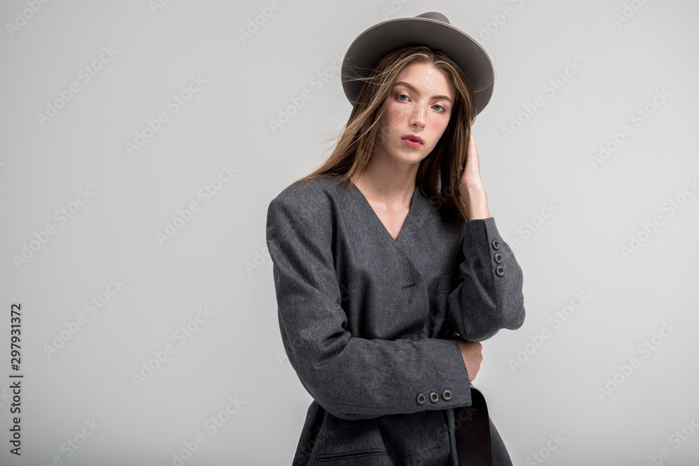 Young girl in trench coat with hat on gray background Young girl in trench coat with hat on gray background