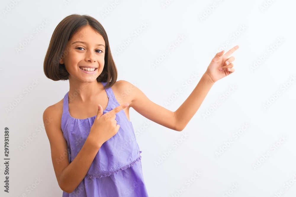 Young beautiful child girl wearing purple casual dress standing over isolated white background smiling and looking at the camera pointing with two hands and fingers to the side. Young beautiful child girl wearing purple casual dress standing over isolated white background smiling and looking at the camera pointing with two hands and fingers to the side.