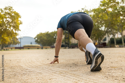 Athletic young man training for a race start in a park at the beginning of Autumn