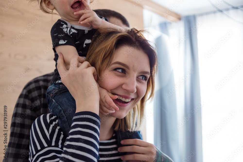 Fototapeta premium Mother giving her baby a piggyback ride around the house.