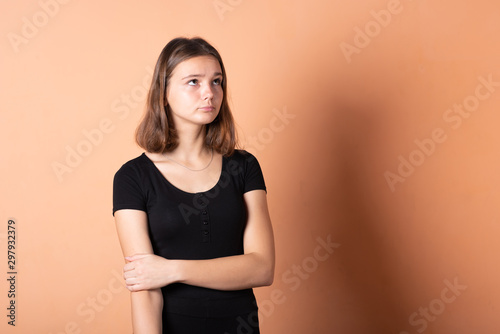 The girl thought and looks up, on a light orange background.