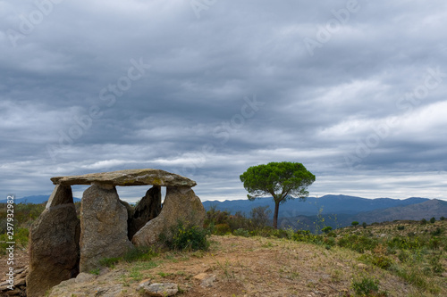 A Megalithic Dolmen in province of Girona, Catalunya, Spain. An ancient megalithic tomb or dolmen on cloudy sky and mountains background.