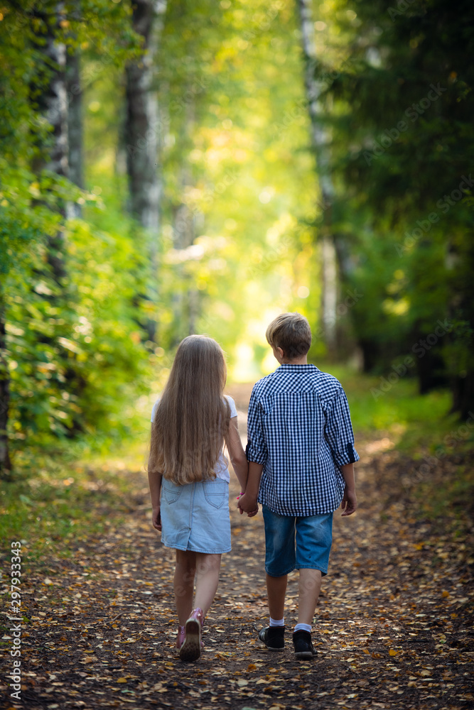 First love. Little boy and girl holding hands and smiling while walking outdoors in park