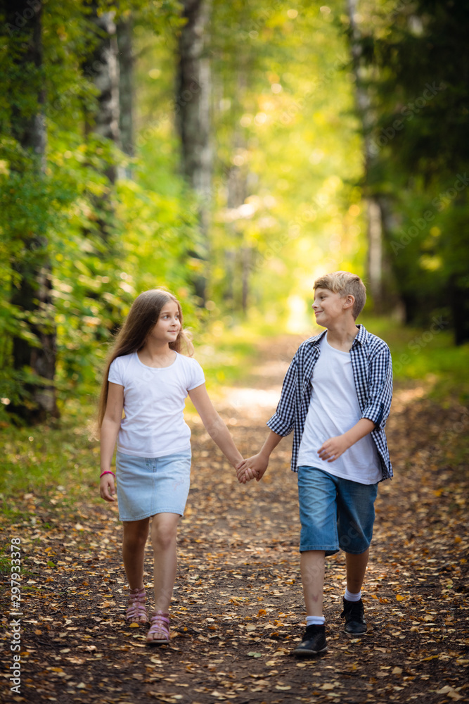 First love. Little boy and girl holding hands and smiling while walking outdoors in park First love. Little boy and girl holding hands and smiling while walking outdoors in park
