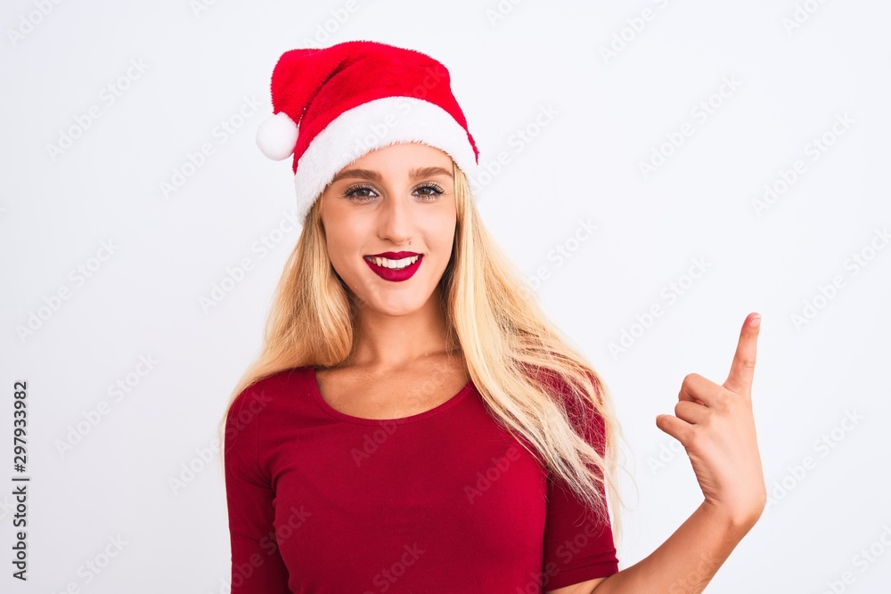 Young beautiful woman wearing Christmas Santa hat over isolated white background showing and pointing up with finger number one while smiling confident and happy. Young beautiful woman wearing Christmas Santa hat over isolated white background showing and pointing up with finger number one while smiling confident and happy.