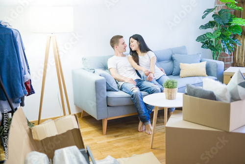 Young beautiful couple sitting on the sofa at new home around cardboard boxes © Krakenimages.com