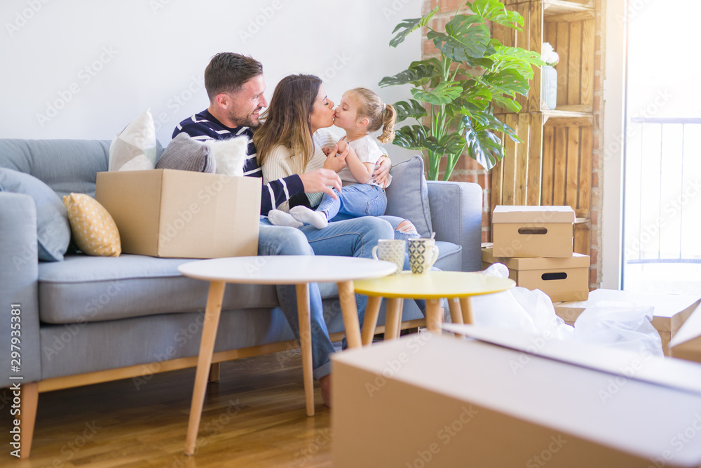 Beautiful family with kid sitting on the sofa drinking coffee at new home around cardboard boxes Beautiful family with kid sitting on the sofa drinking coffee at new home around cardboard boxes