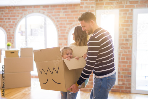 Beautiful famiily, kid playing with his parents riding fanny cardboard box at new home photo