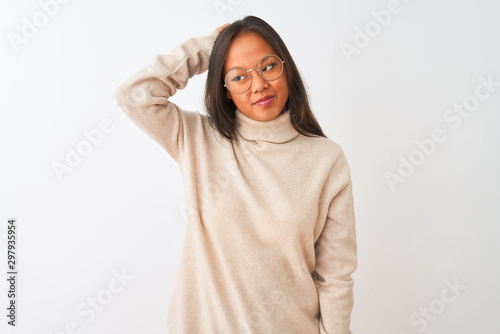 Young chinese woman wearing turtleneck sweater and glasses over isolated white background confuse and wonder about question. Uncertain with doubt, thinking with hand on head. Pensive concept. © Krakenimages.com