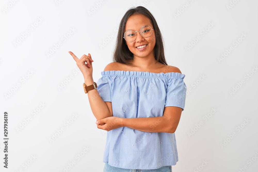 Young chinese woman wearing blue t-shirt and glasses over isolated white background with a big smile on face, pointing with hand and finger to the side looking at the camera. Young chinese woman wearing blue t-shirt and glasses over isolated white background with a big smile on face, pointing with hand and finger to the side looking at the camera.