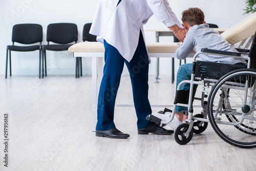 Young male doctor pediatrist and boy in wheel-chair