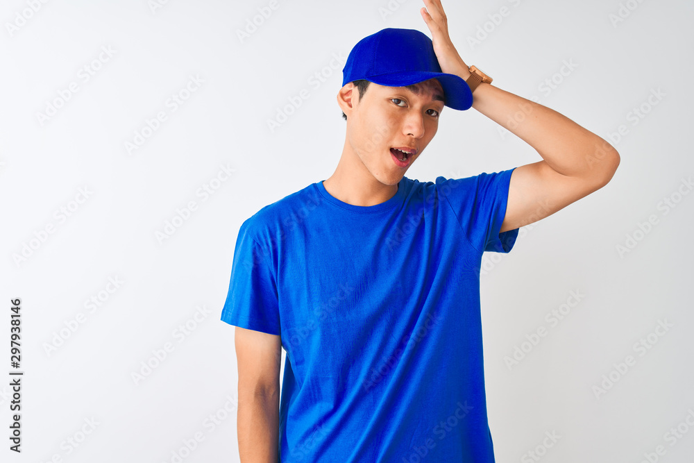 Chinese deliveryman wearing blue t-shirt and cap standing over isolated white background surprised with hand on head for mistake, remember error. Forgot, bad memory concept. Chinese deliveryman wearing blue t-shirt and cap standing over isolated white background surprised with hand on head for mistake, remember error. Forgot, bad memory concept.