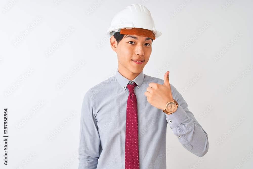 Chinese architect man wearing tie and helmet standing over isolated white background doing happy thumbs up gesture with hand. Approving expression looking at the camera showing success.
