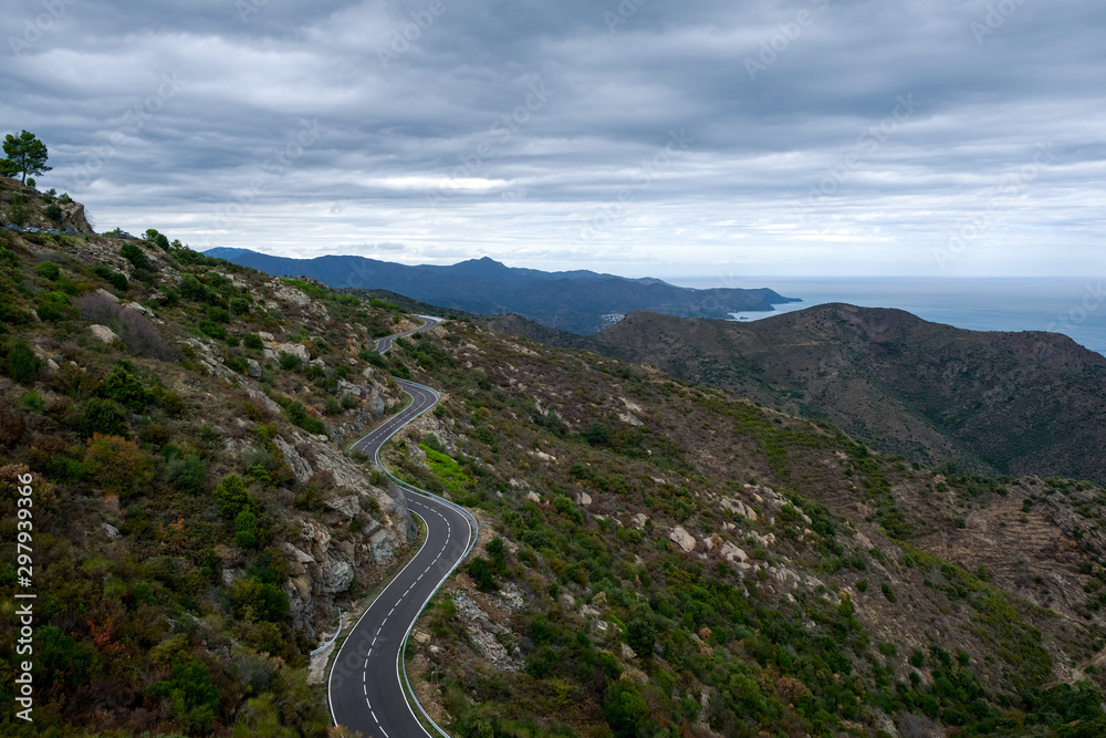 Beautiful mountain road in Catalunya, Spain. Serpentine mountain route in Europe on cloudy sky background. Curved asphalt road running along the sea. Vacation and travel by car concept.