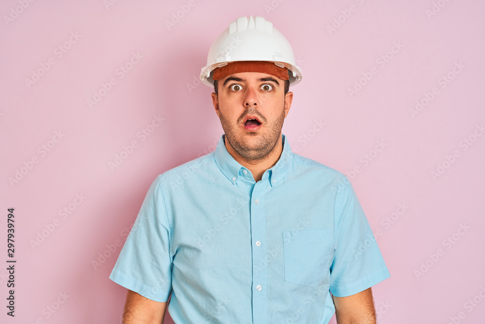 Young architect man wearing security helmet standing over isolated pink background afraid and shocked with surprise expression, fear and excited face. Young architect man wearing security helmet standing over isolated pink background afraid and shocked with surprise expression, fear and excited face.
