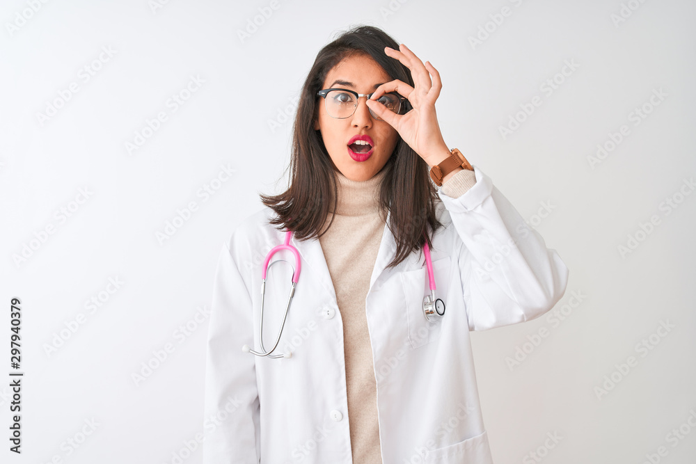 Chinese doctor woman wearing coat and pink stethoscope over isolated white background doing ok gesture shocked with surprised face, eye looking through fingers. Unbelieving expression. Chinese doctor woman wearing coat and pink stethoscope over isolated white background doing ok gesture shocked with surprised face, eye looking through fingers. Unbelieving expression.