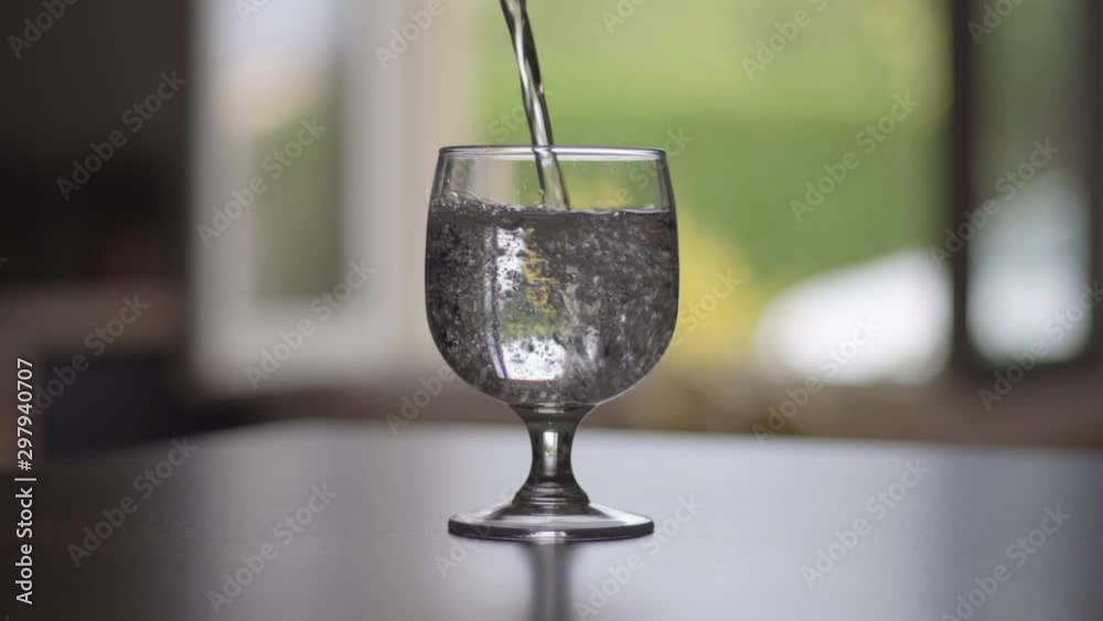 Eau fraîche versée dans un verre transparent. Gros plan.