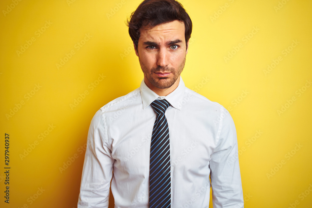 Young handsome businessman wearing elegant shirt and tie over isolated yellow background skeptic and nervous, frowning upset because of problem. Negative person. Young handsome businessman wearing elegant shirt and tie over isolated yellow background skeptic and nervous, frowning upset because of problem. Negative person.