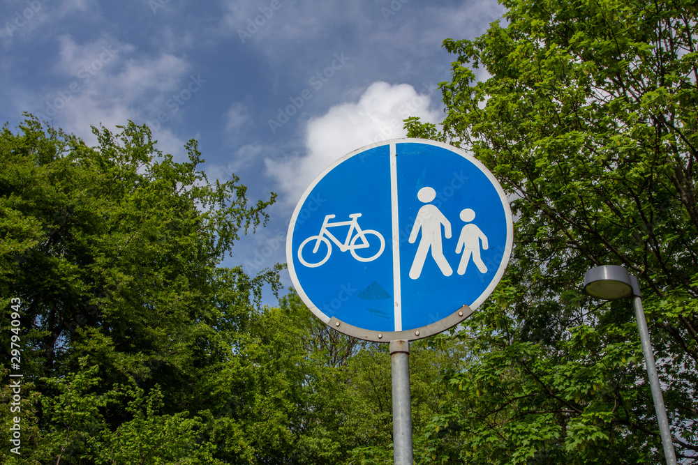 road sign of bike and humans with blue sky and clouds