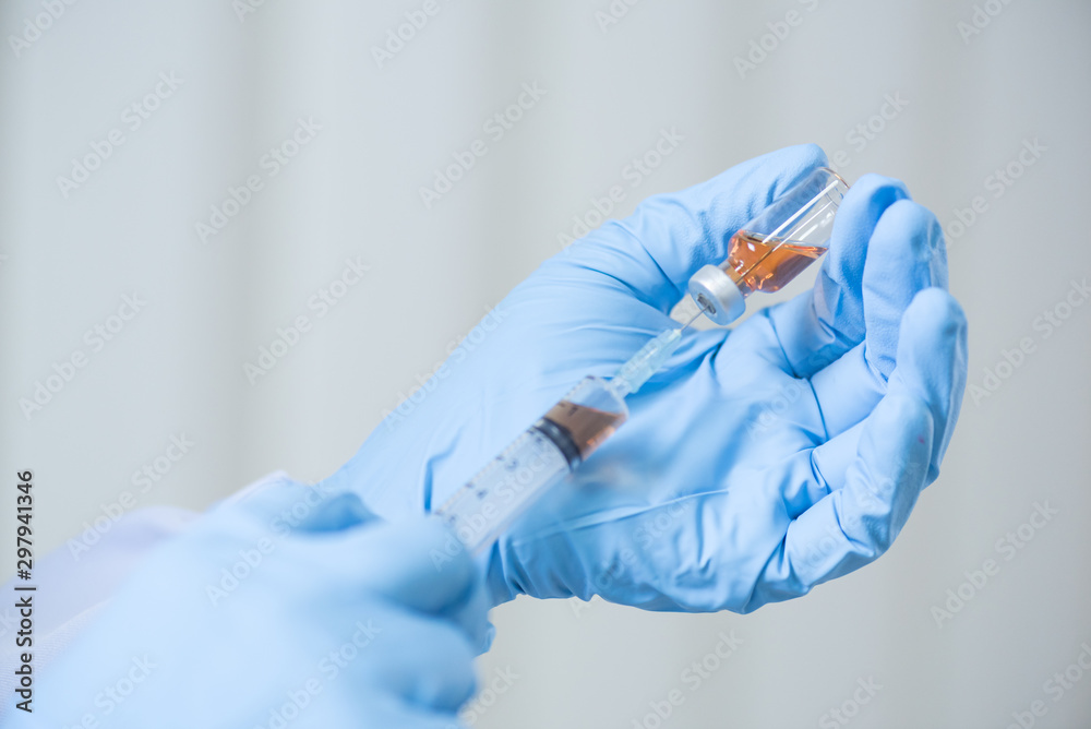 Fototapeta premium Close up doctor's hand holding medicine bottle and syringe for vaccine to patient on blue tone.Nurse using syringe are vaccination to patient for influenza protection.Medication treatment concept.