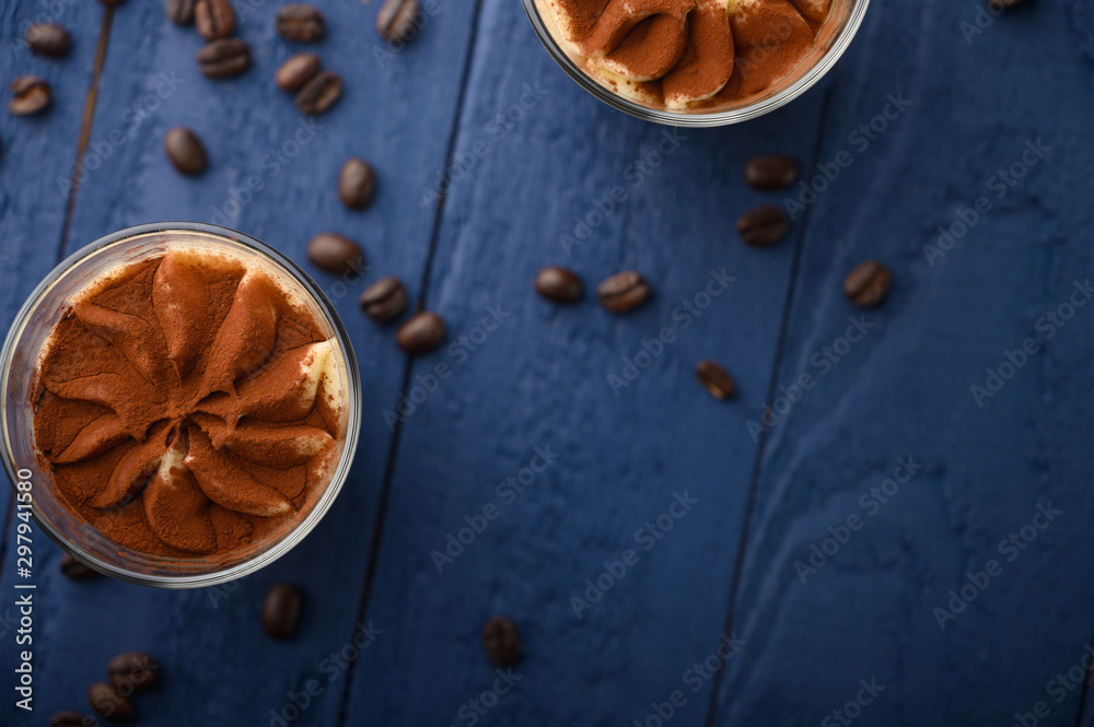 flat lay, Tiramisu two glasses with coffee grains on a blue wooden background. With space for design flat lay, Tiramisu two glasses with coffee grains on a blue wooden background. With space for design