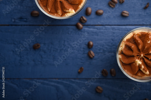flat lay, Tiramisu two glasses with coffee grains on a blue wooden background. With space for design