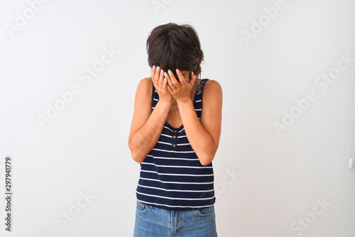 Young beautiful woman wearing striped t-shirt standing over isolated white background with sad expression covering face with hands while crying. Depression concept. © Krakenimages.com