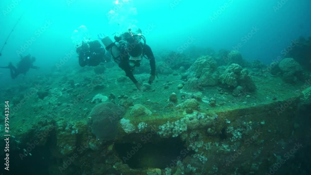 Divers in Truk Lagoon of shipwreck on Chuuk Islands. Shipwreck in historic place of tragedy of WW II and diving among wreckage of ship.