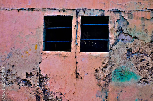 Grungy jouful pink wall with two dark barred windows, love is a prison concept. © Daguimagery