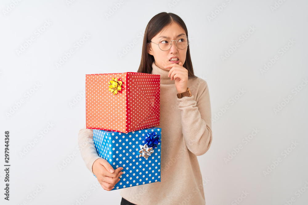 Young chinese woman holding birthday gifts over isolated white background Thinking worried about a question, concerned and nervous with hand on chin Young chinese woman holding birthday gifts over isolated white background Thinking worried about a question, concerned and nervous with hand on chin
