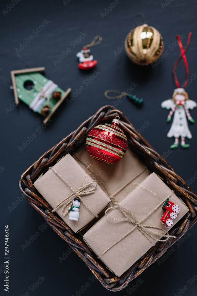 Vertical flat lay photo of Christmas presents and fir toys. Gift boxes wrapped in kraft paper, golden ball, white angel and green house. Home decoration. Happy New Year mood. Merry Christmas concept. Vertical flat lay photo of Christmas presents and fir toys. Gift boxes wrapped in kraft paper, golden ball, white angel and green house. Home decoration. Happy New Year mood. Merry Christmas concept.
