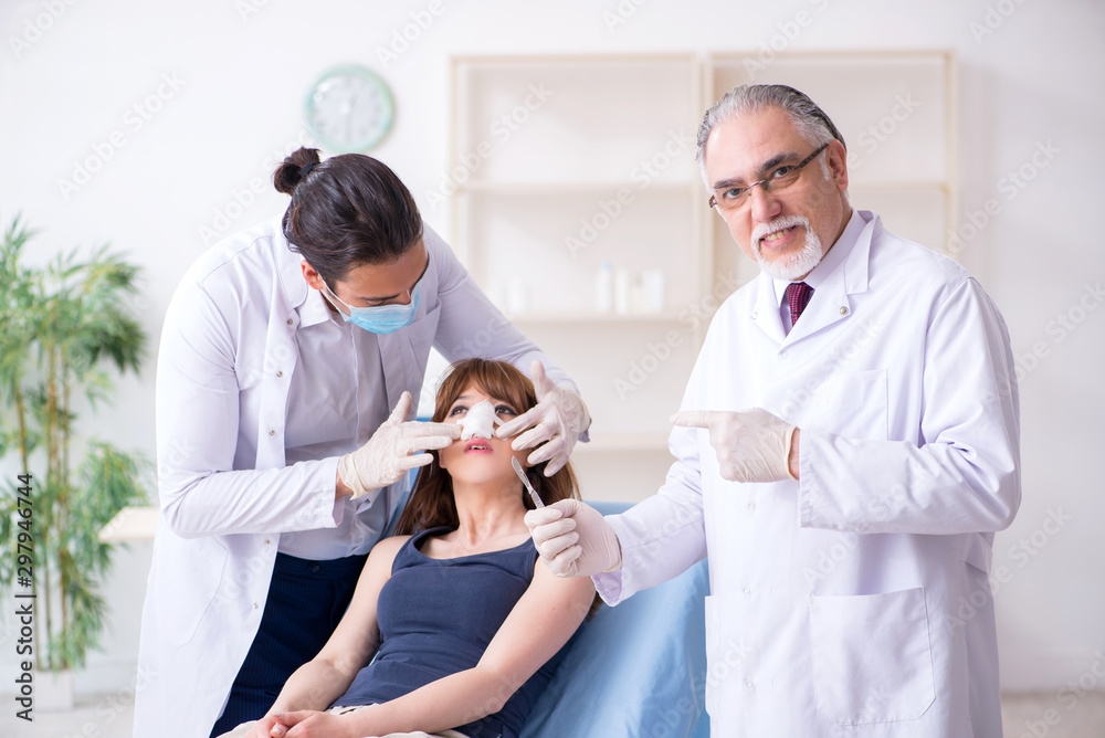 Obraz premium Two male doctors and young woman in plastic surgery concept