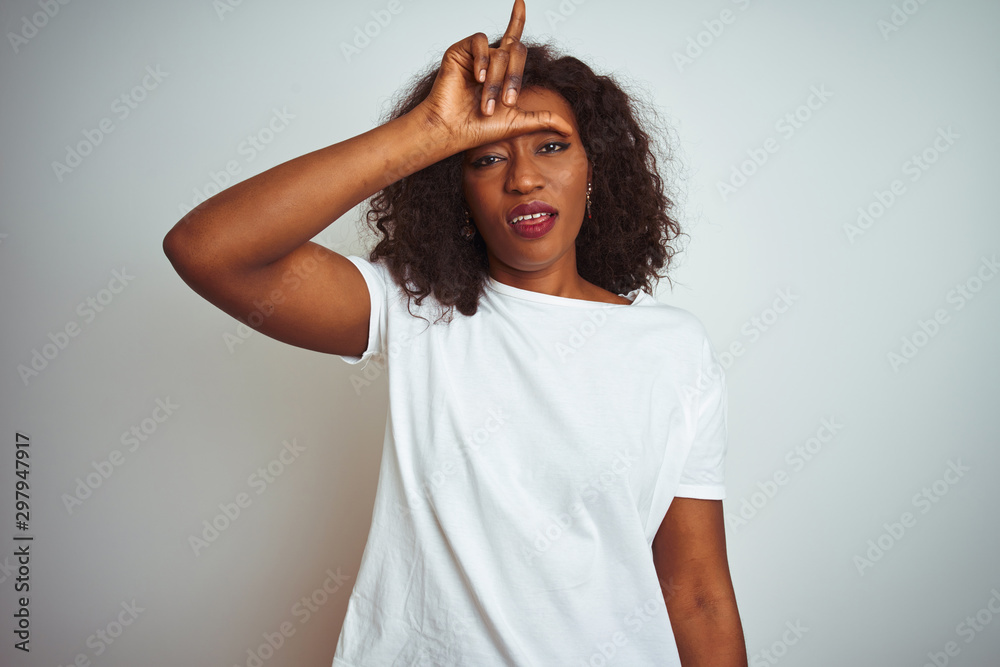 Young african american woman wearing t-shirt standing over isolated white background making fun of people with fingers on forehead doing loser gesture mocking and insulting. Young african american woman wearing t-shirt standing over isolated white background making fun of people with fingers on forehead doing loser gesture mocking and insulting.